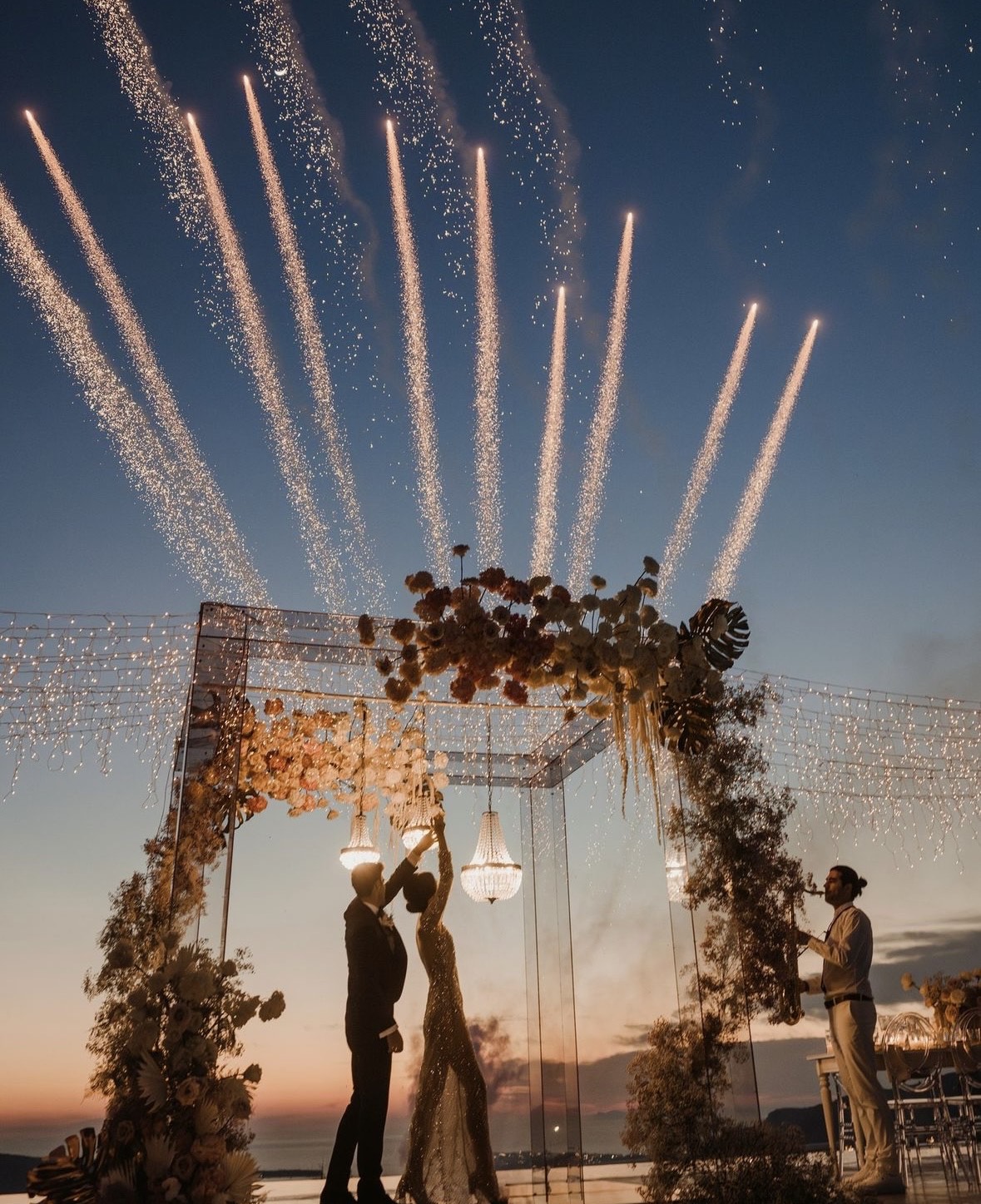Jets of light rising over a floral arch at sunset, Santorini