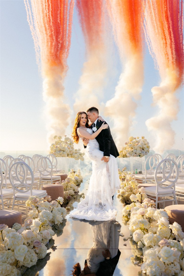 Peach coloured smoke rising behind a ceremony aisle