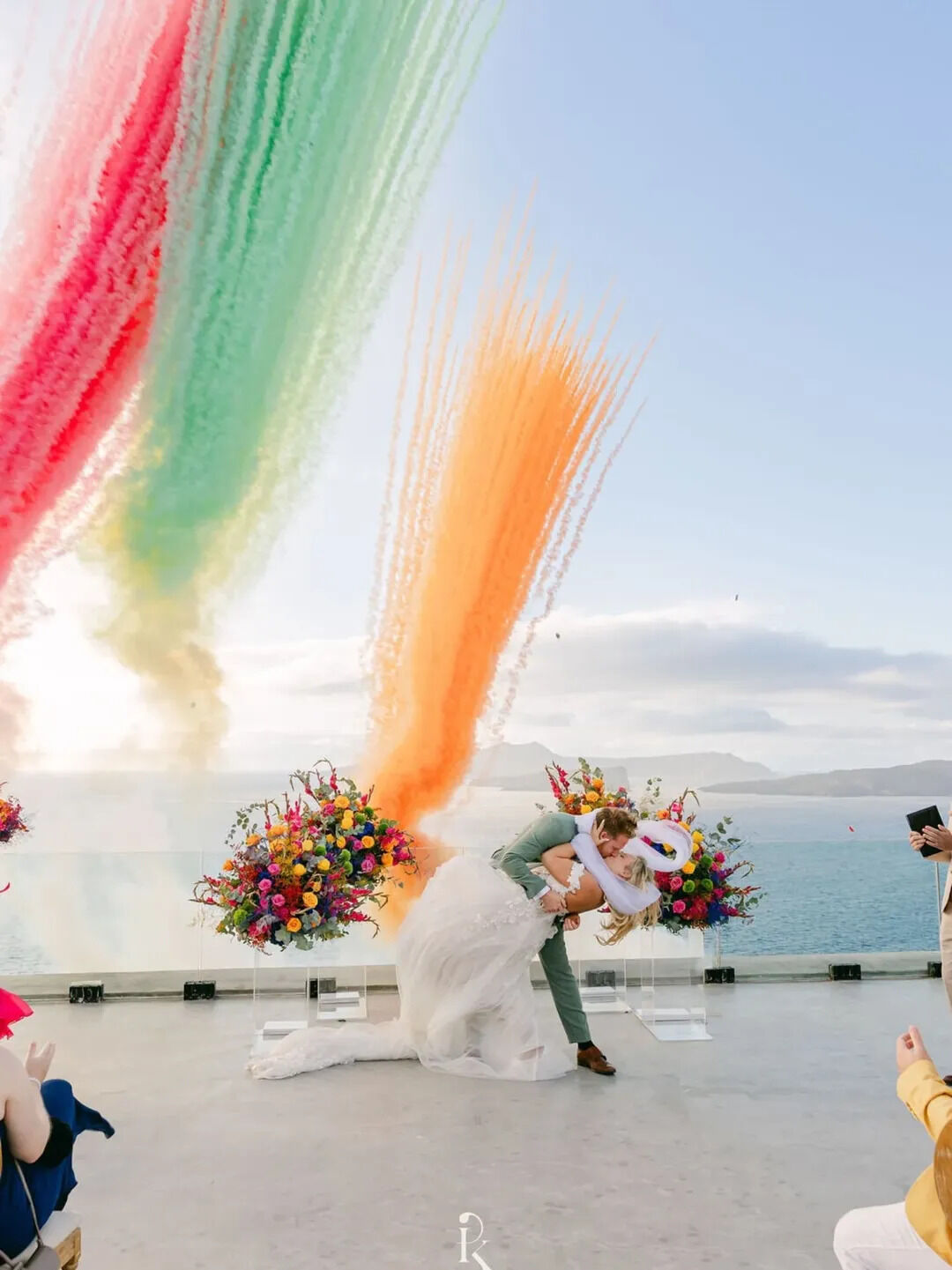 Pink, green and orange smoke columns over a caldera ceremony