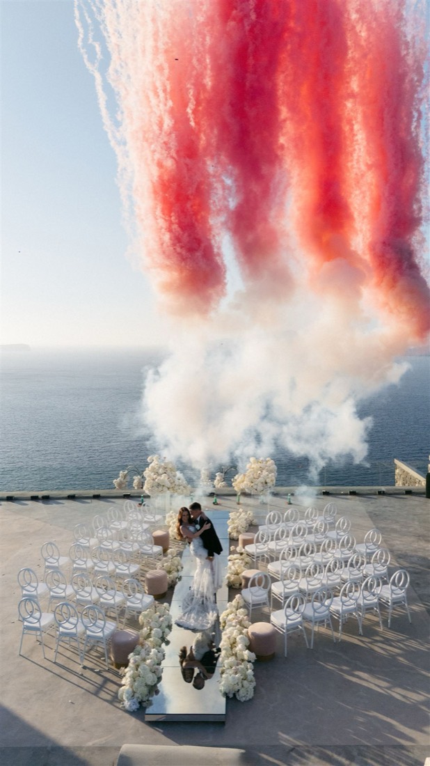 Red smoke columns over the sea above a ceremony